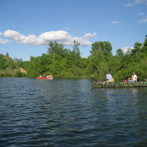 Two boats with people fishing on a small lake.